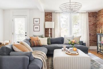 Mid-century modern living room with charcoal sectional, brick wall, and warm neutral accents