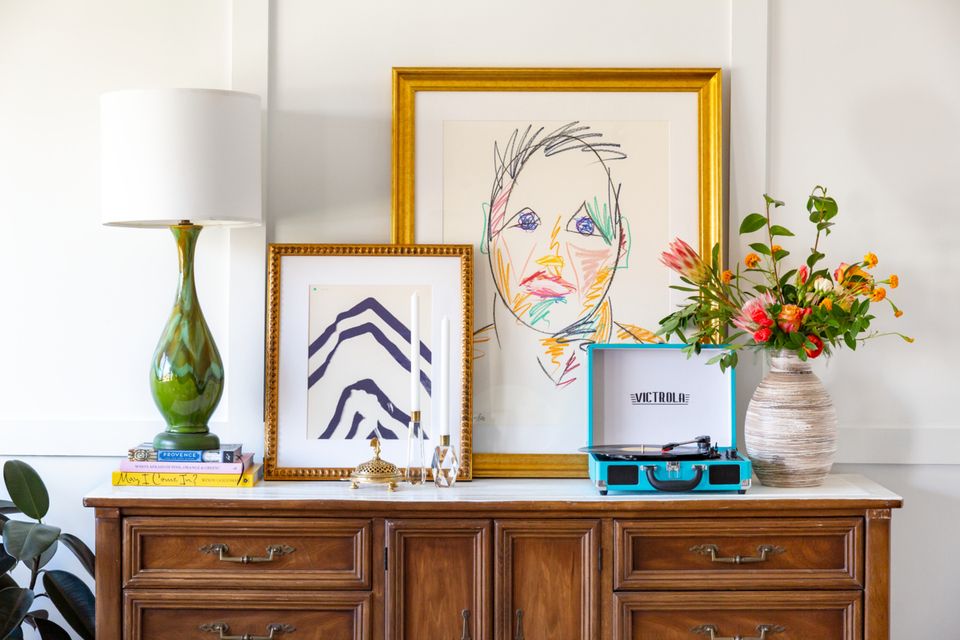 Eclectic gallery arrangement on wood dresser with gold and natural frames, botanical accents