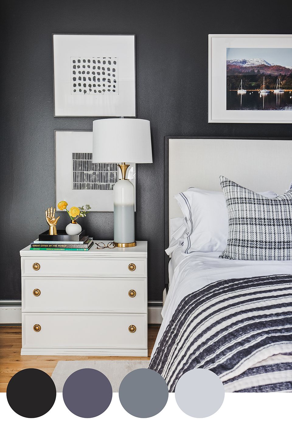 Contemporary bedroom featuring charcoal accent wall, navy striped bedding, and white nightstand with brass hardware for a modern, masculine aesthetic.