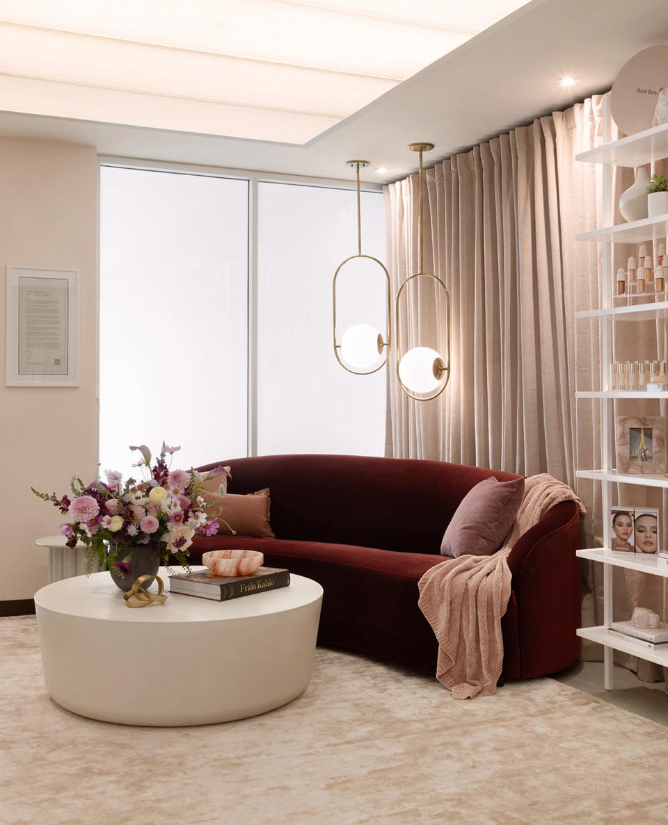 Sophisticated lounge with burgundy sofa, sculptural pendant lights, and cream round table