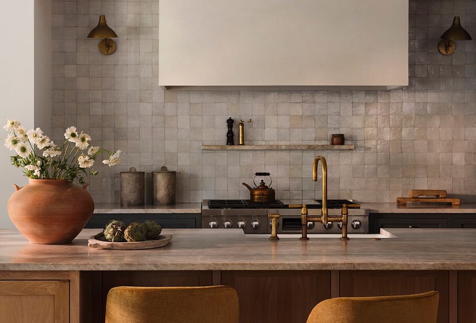 Warm contemporary kitchen with terracotta pottery, brass fixtures, and soft gray subway tile backsplash