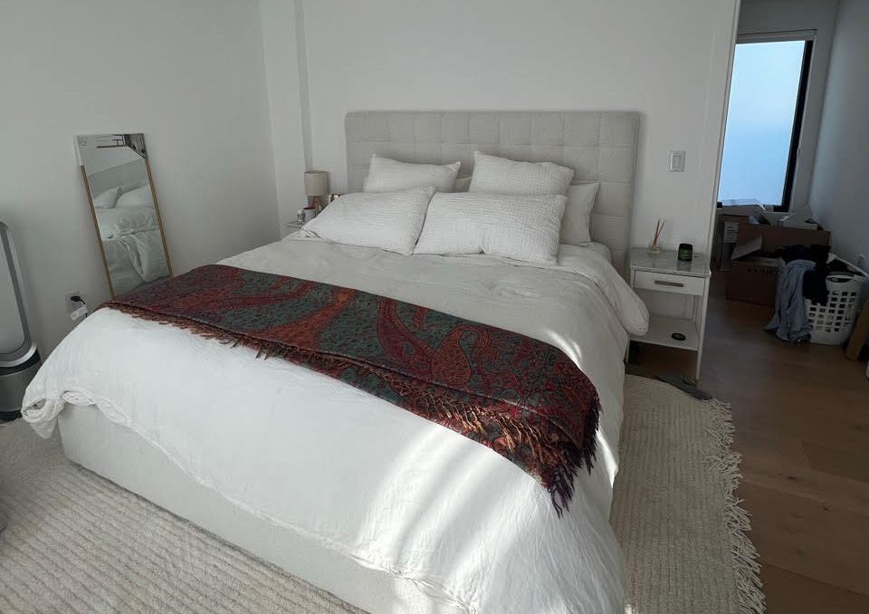 Minimalist bedroom with soft gray upholstered headboard and warm neutral tones creating a peaceful, restful sanctuary.