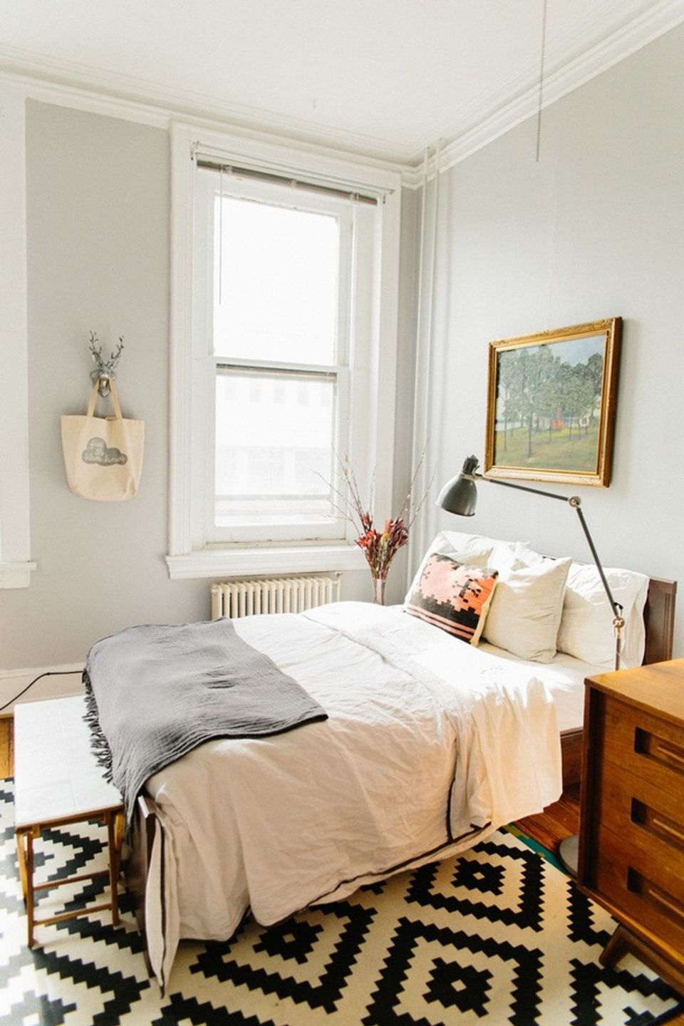 Scandinavian dorm room with warm wood furniture, geometric rug, and minimal neutral palette
