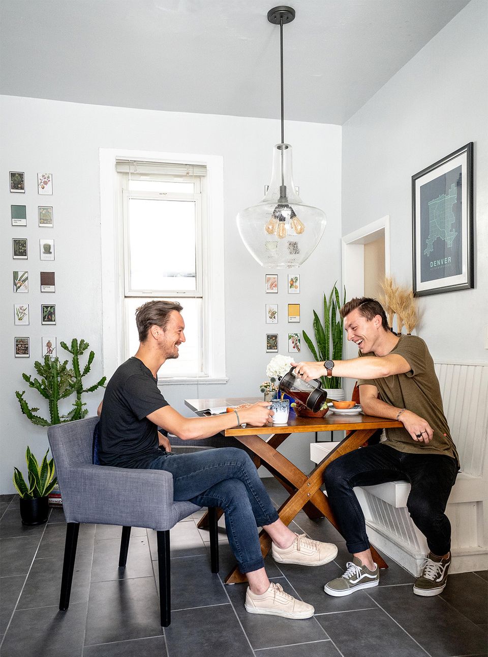 Scandinavian-inspired small dining nook with wooden table, pendant light, and potted plants creating warm, intimate workspace.