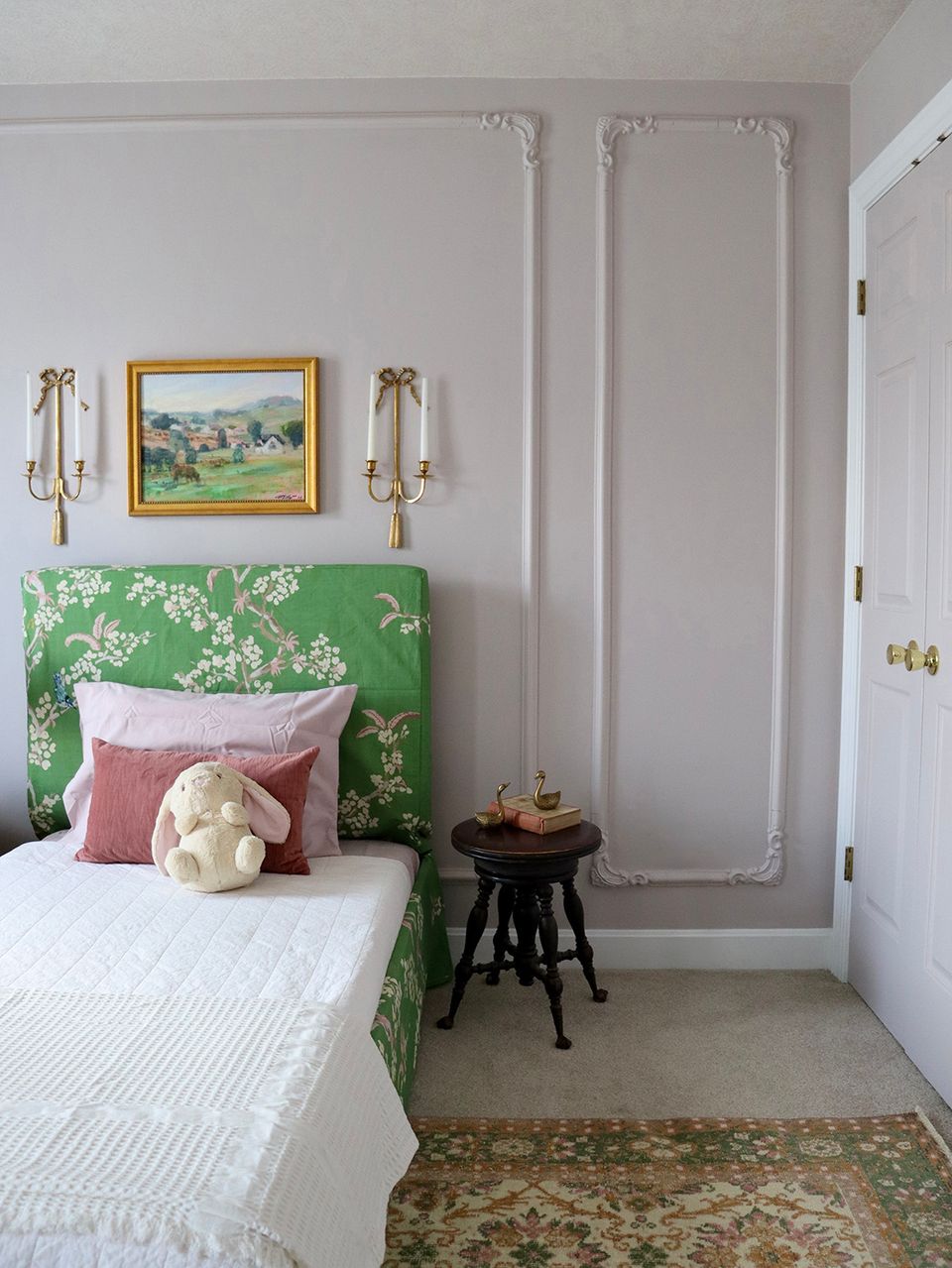 Eclectic bedroom with vibrant green botanical accent wall, pink pillow, and gallery wall styling