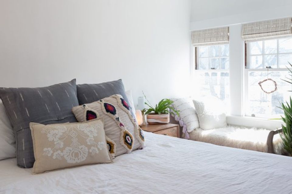 Minimalist bedroom with gray bedding, geometric pillows, and bright natural light from windows