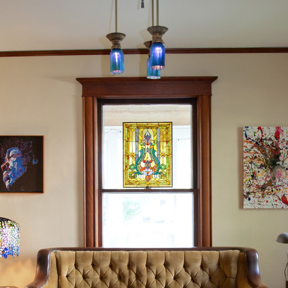 Traditional dining room with rich wood trim, stained glass window art, and tufted leather banquette