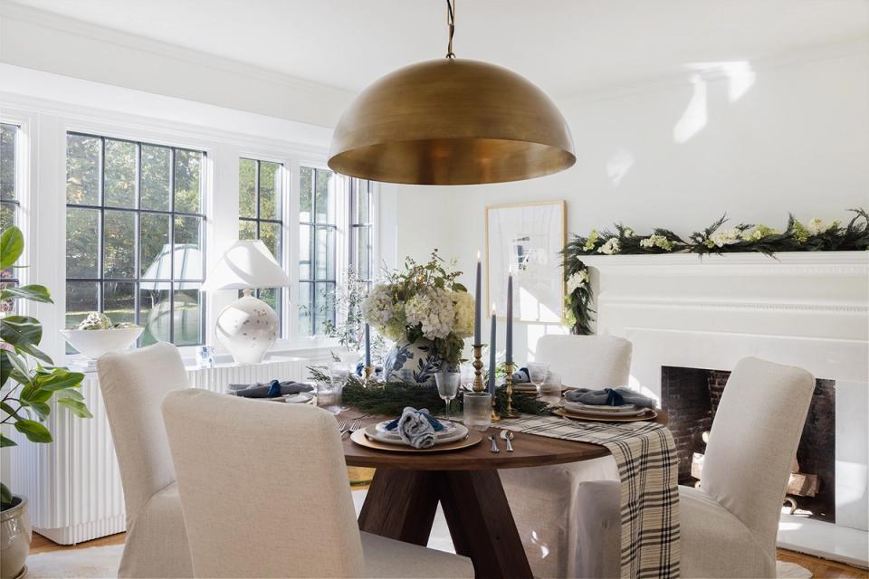 Modern minimalist holiday tablescape with warm brass pendant, neutral tones, and subtle greenery garland