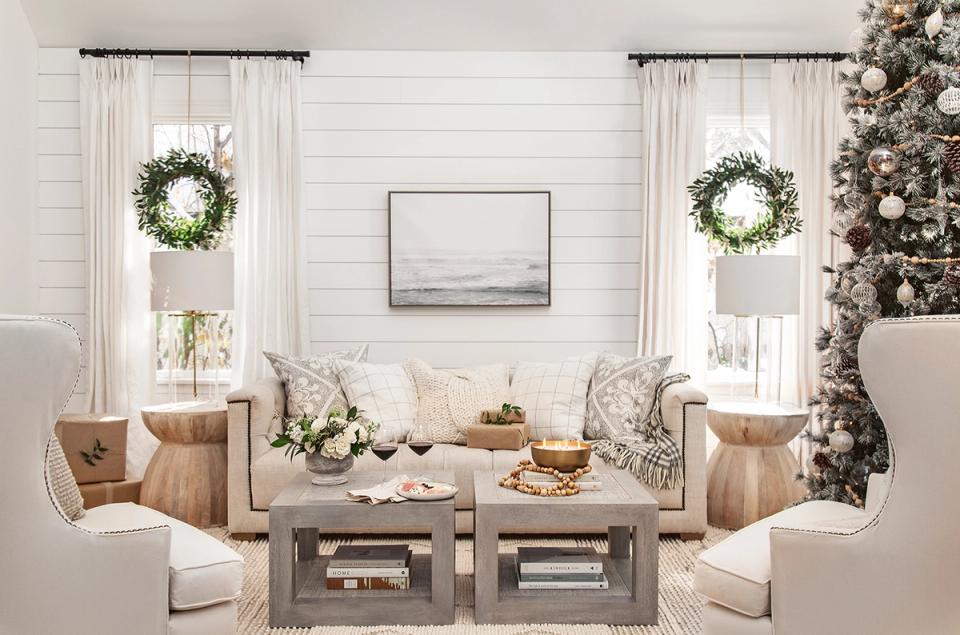 Serene living room with cream and taupe tones, simple wreaths, and understated holiday elegance near windows