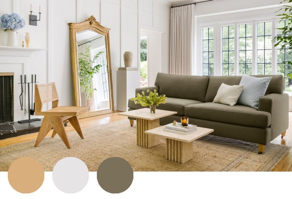 Contemporary living room featuring sage green sofa, natural wood accents, golden mirror, and neutral layered palette with botanical elements.