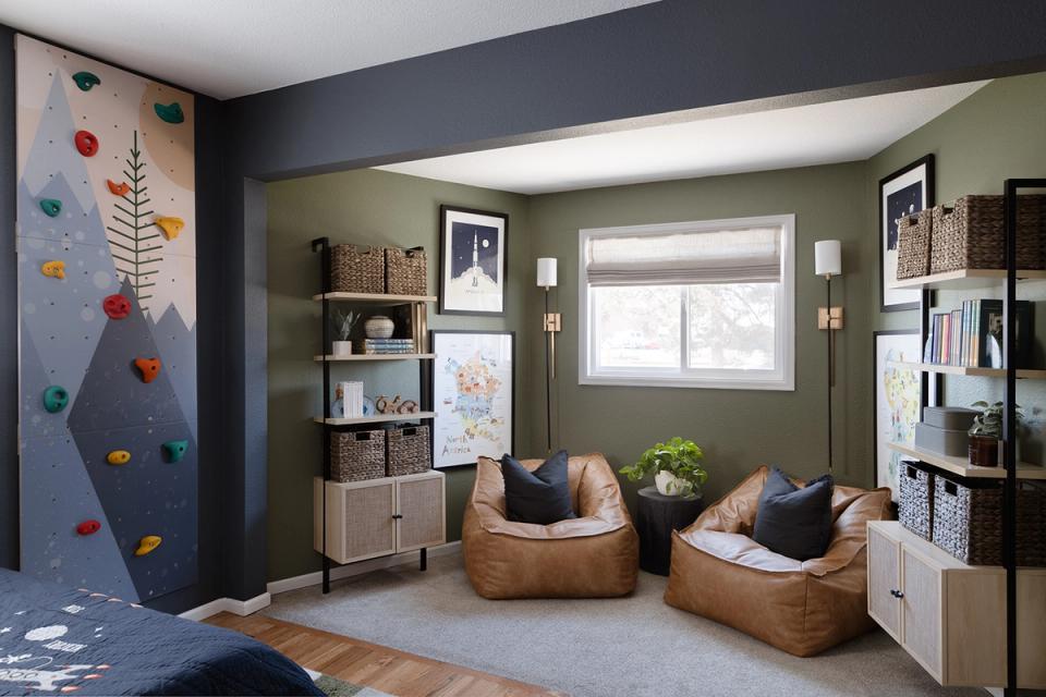 Sage green bedroom with dual tan leather seating, climbing wall accent, and curated shelving creating a nature-inspired, adventurous atmosphere