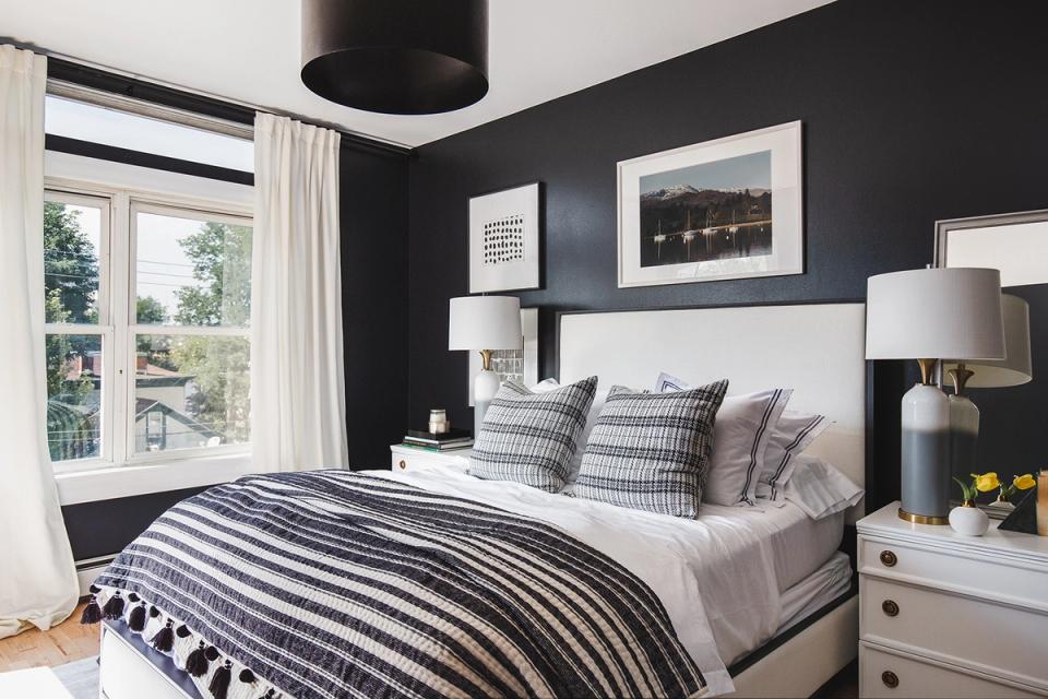 Contemporary bedroom with dramatic charcoal walls, striped bedding, and clean white accents