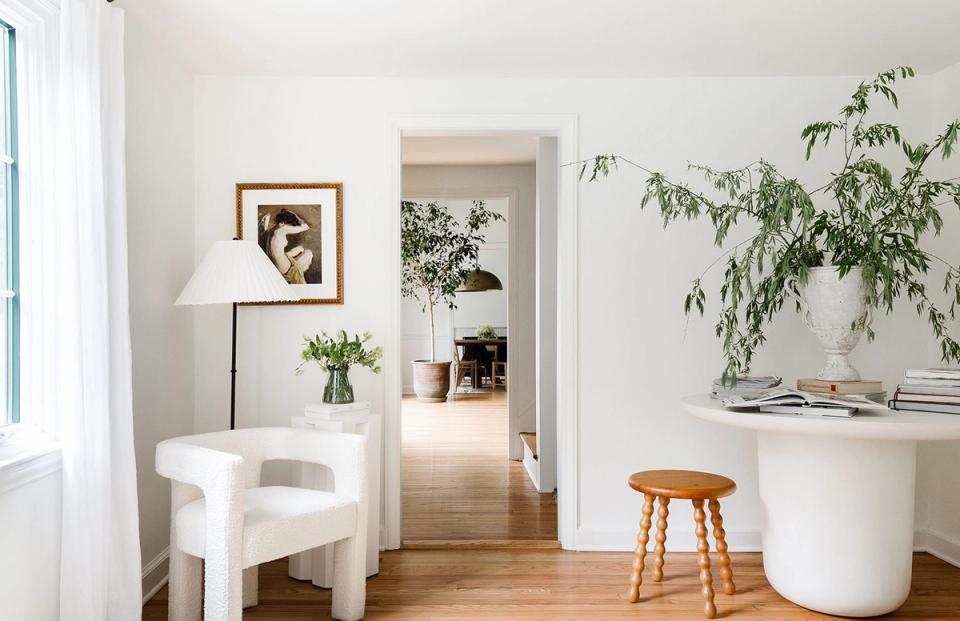Minimalist white interior with natural wood accents, potted greenery, and soft neutral tones