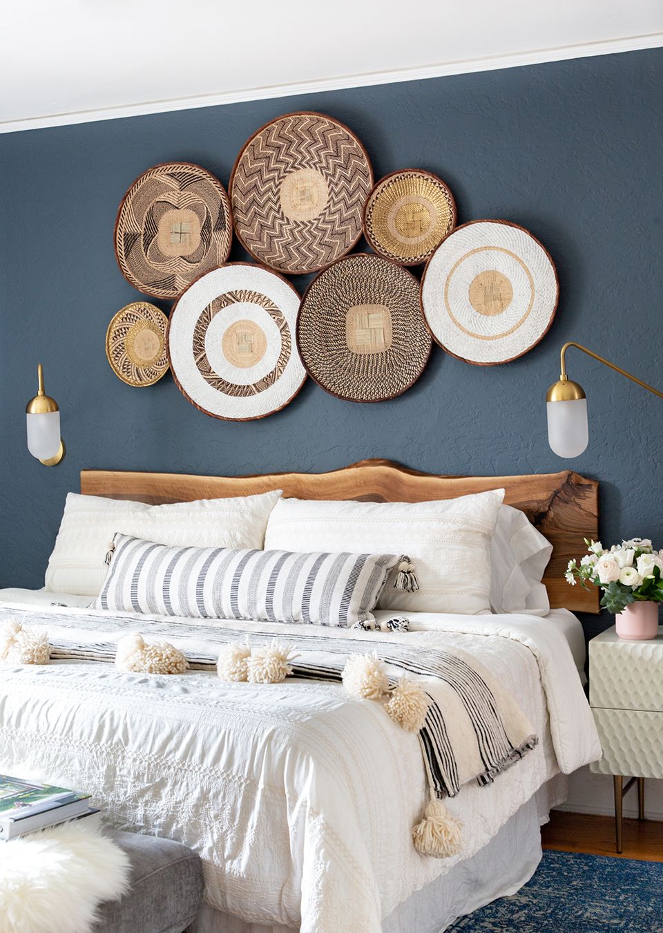 Coastal-inspired bedroom with slate blue accent wall, woven plate wall art, and striped bedding