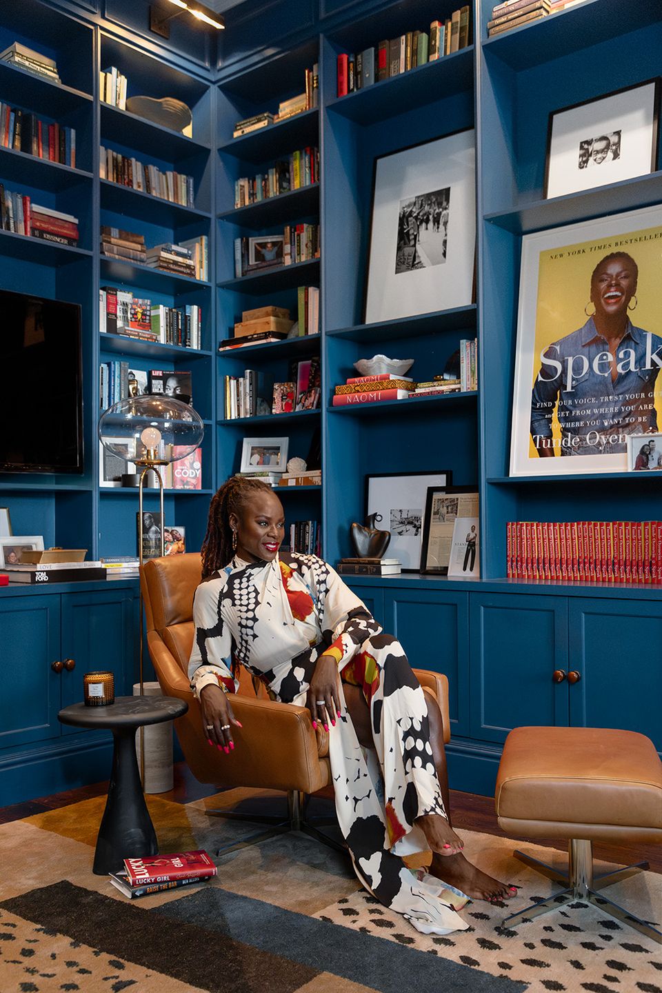 Bold jewel-tone library with deep blue walls, cognac leather chair, curated shelving, and vibrant art creating sophisticated, literary atmosphere