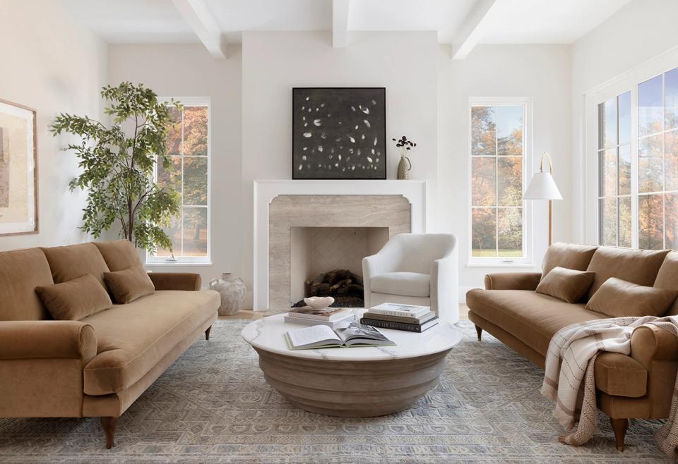 Bright transitional living room with caramel sofas, wooden coffee table, and natural light