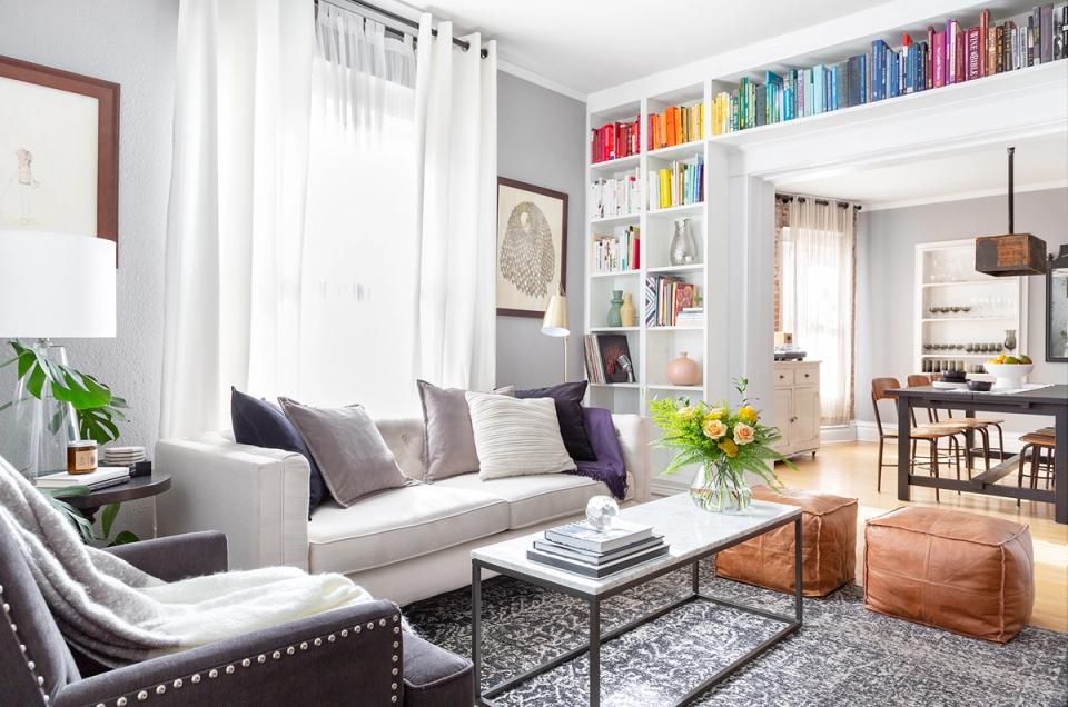Contemporary gray living room with colorful bookshelf accents, light upholstery, and warm wood coffee table creating balanced visual interest