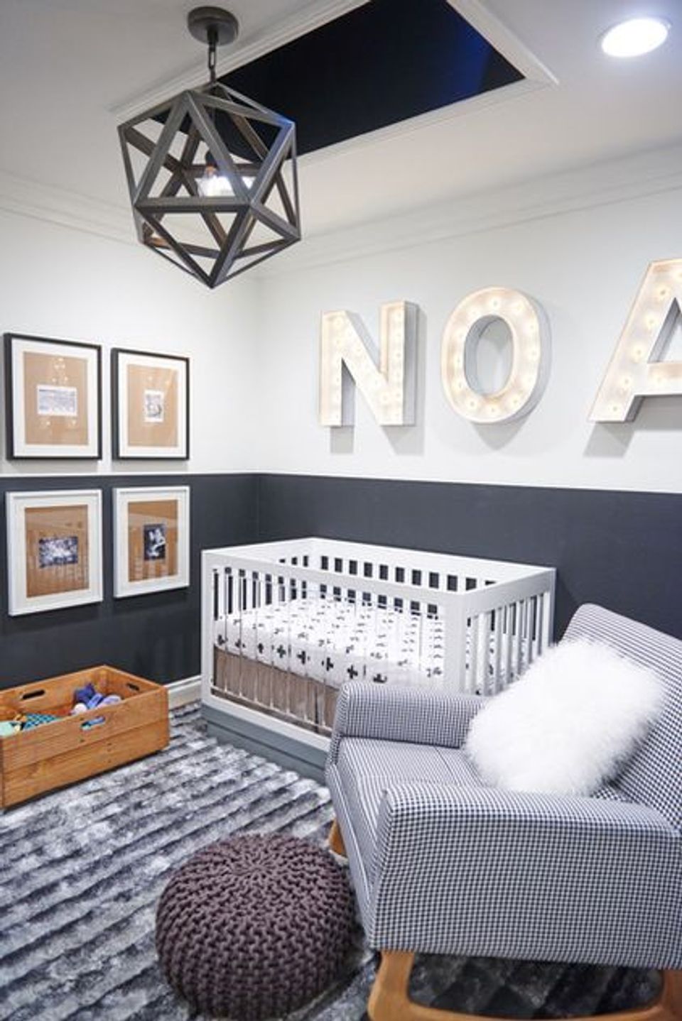 Modern nursery with navy and white two-tone walls, graphic art, geometric pendant light, and minimalist aesthetic.