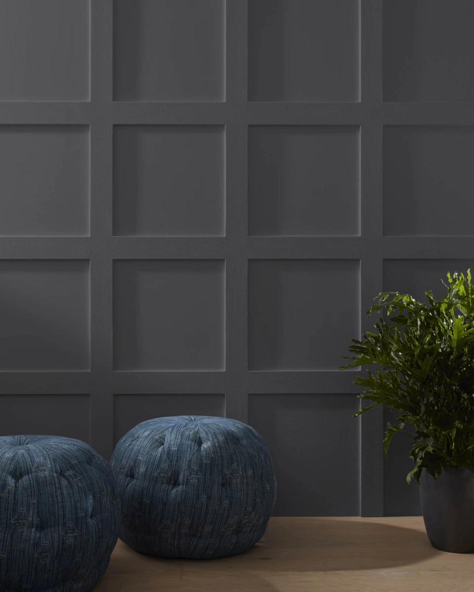 Sophisticated paneled wall in deep gray with modern geometric pattern and textured blue poufs for dramatic contemporary appeal