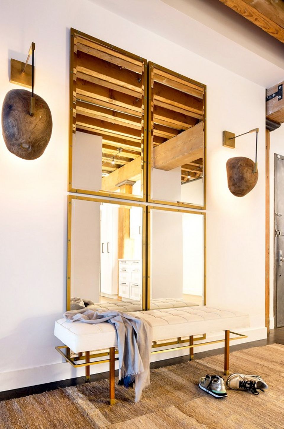 Scandinavian-inspired bedroom with brass-framed mirror headboard and natural wood flooring