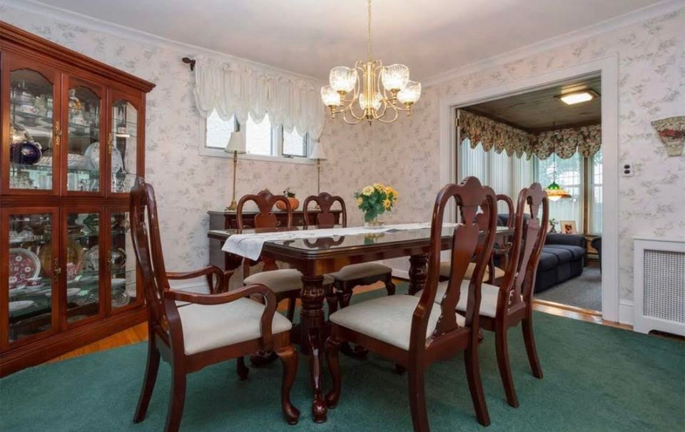 Traditional formal dining with dark wood furniture and patterned wallpaper