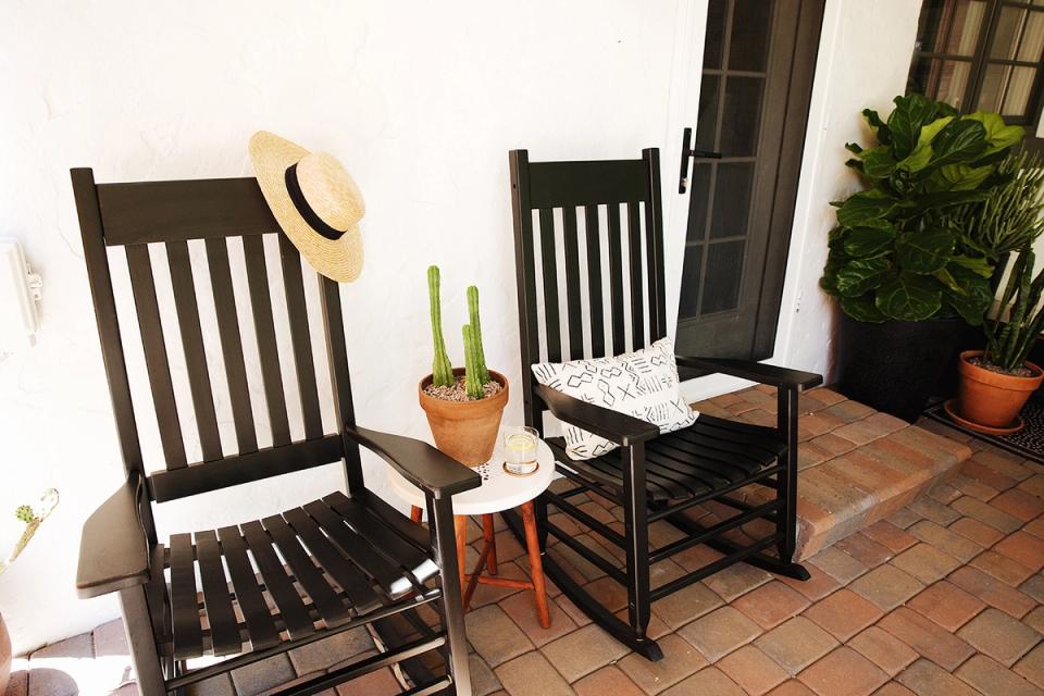 Rustic Spanish colonial patio with black wooden rockers, terra cotta tiles, and warm Mediterranean countryside charm.