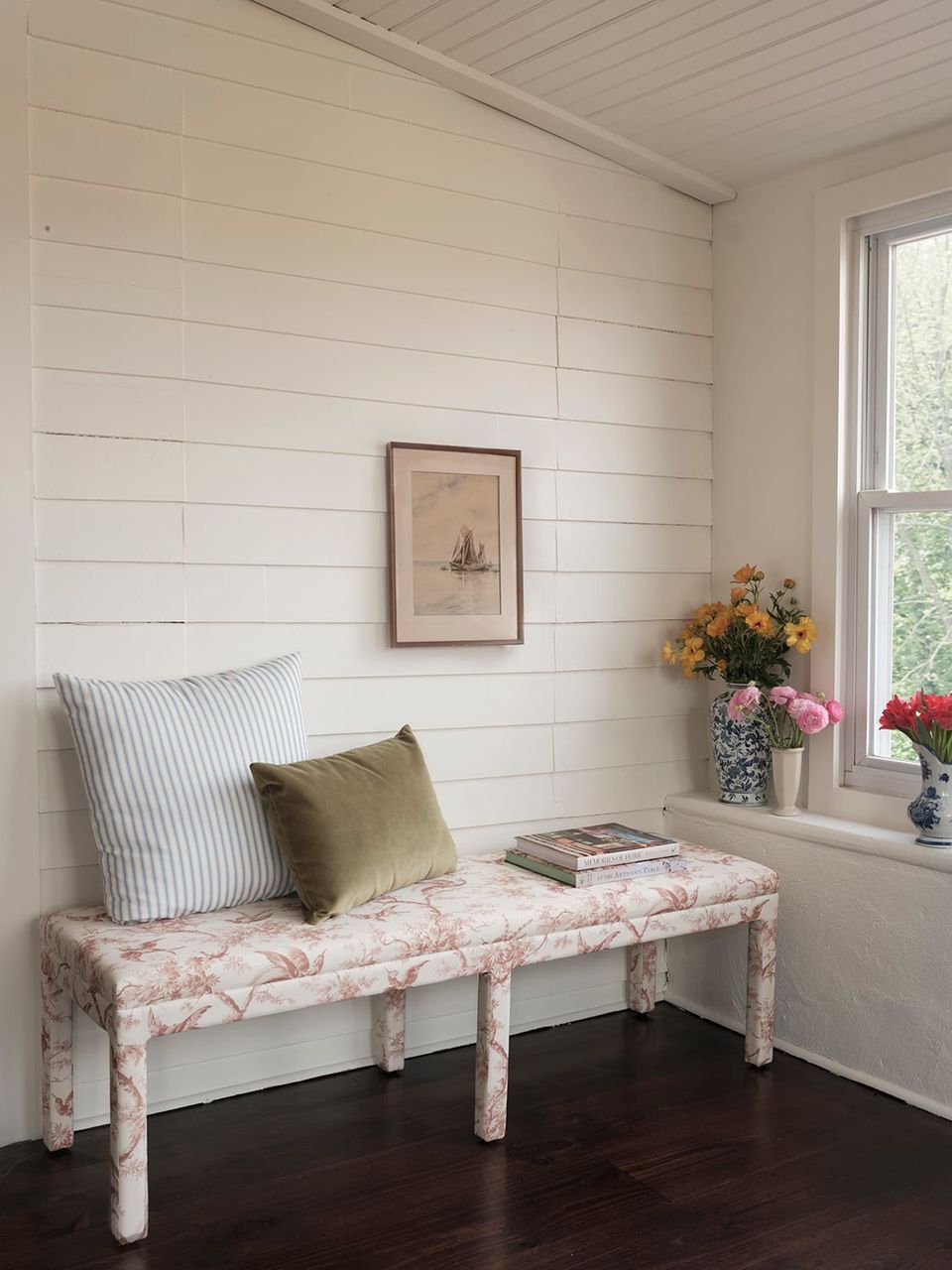 Farmhouse entryway with shiplap walls, floral upholstered bench, striped pillow, and fresh flower arrangement
