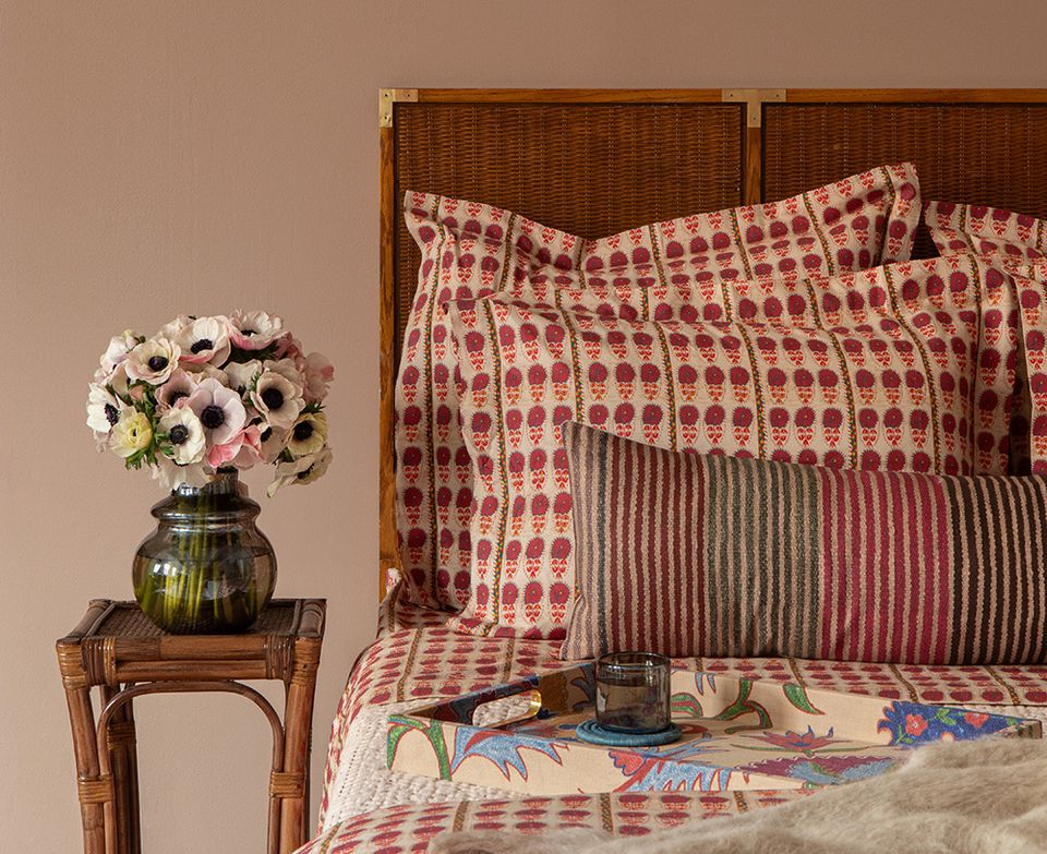 Eclectic bedroom with warm terracotta tones, mixed geometric and floral patterns on bedding and pillows