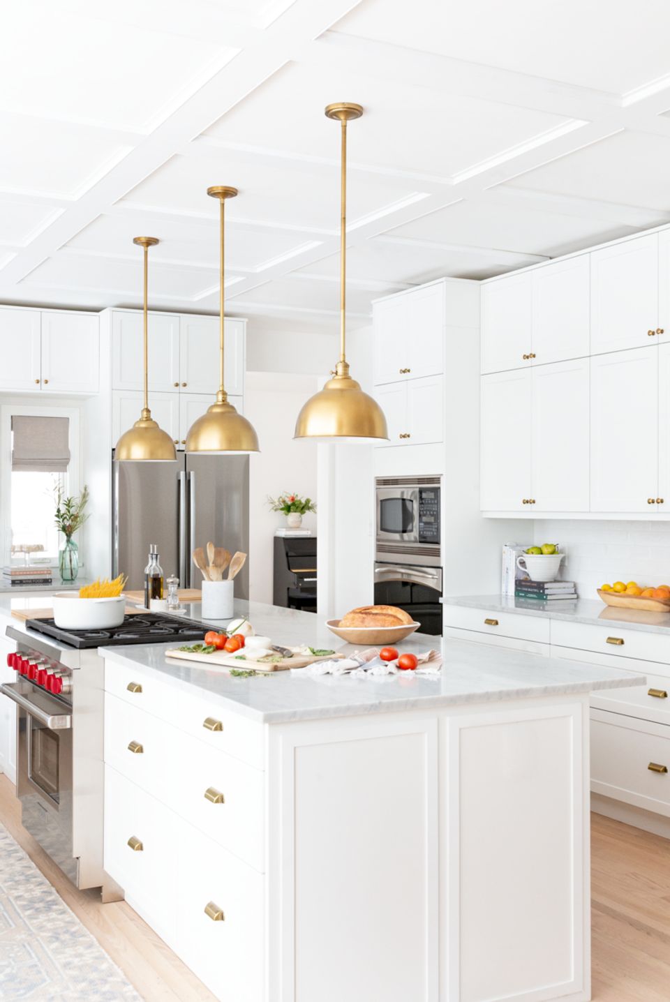 Bright minimalist kitchen with white cabinetry, gold dome pendants, and marble island