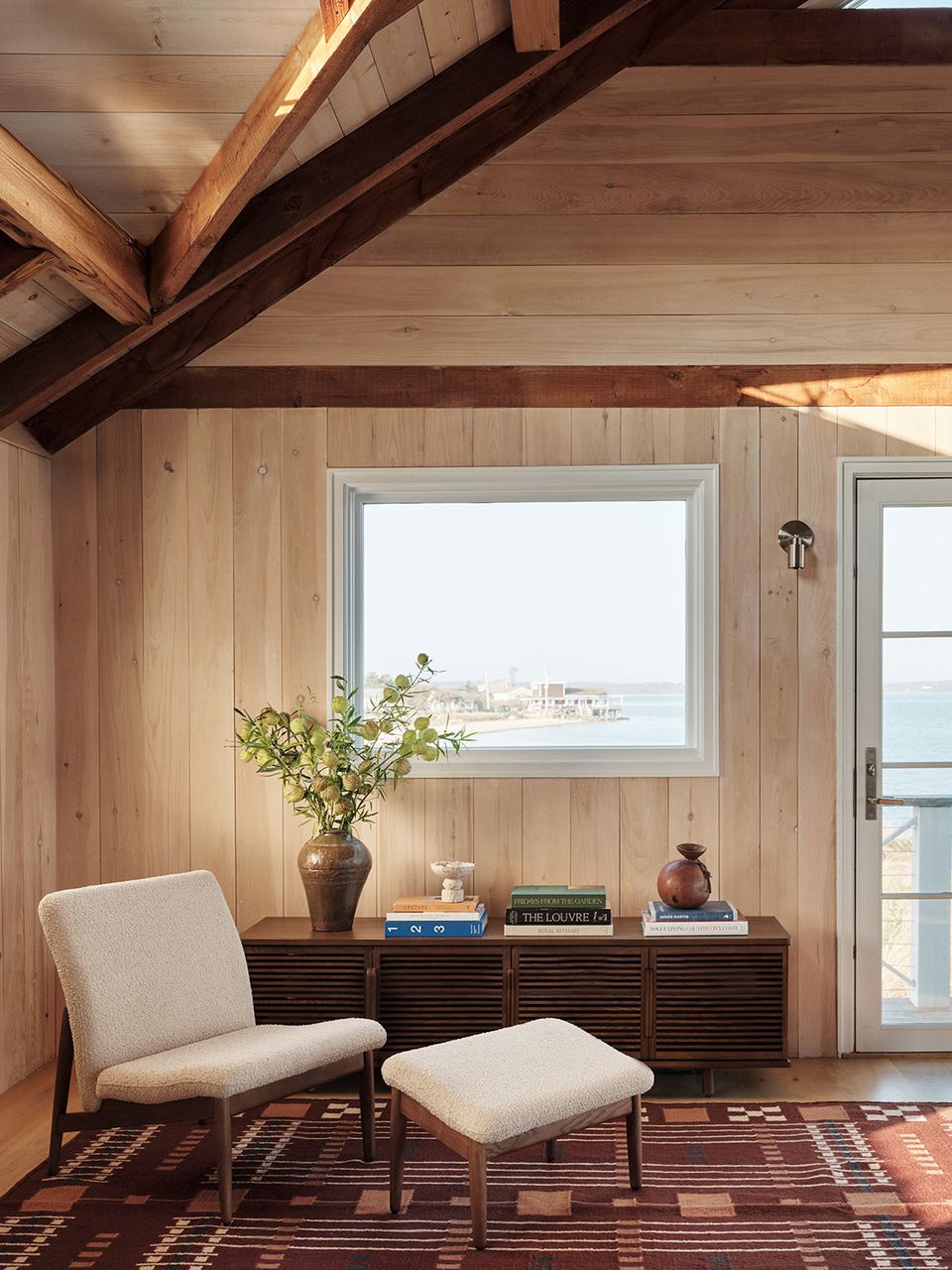 Coastal modern retreat with exposed wood beams, nautical striped chair, and ocean view