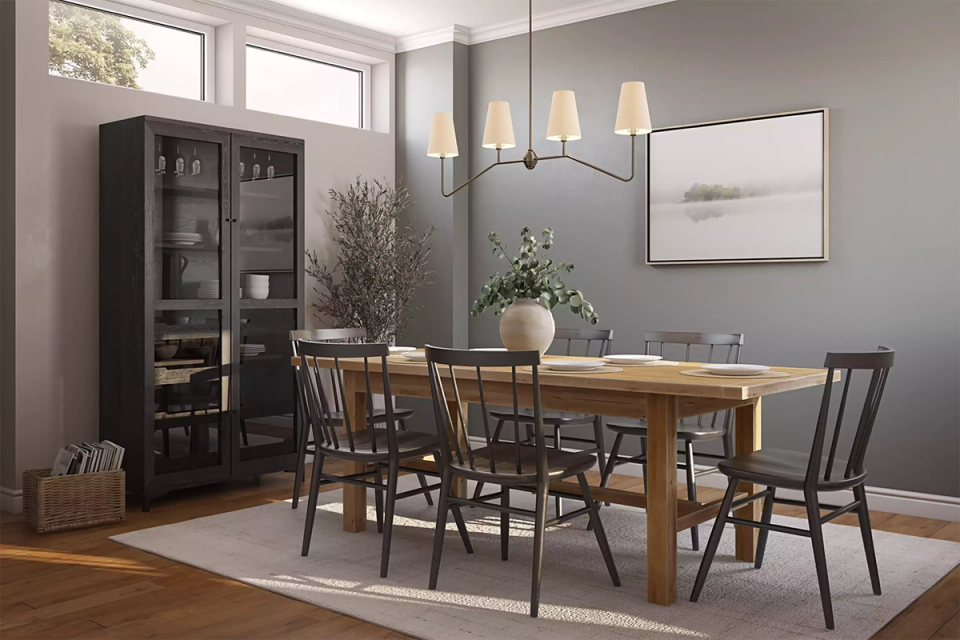Sophisticated dining room with gray-taupe walls, wood table, black chairs, and warm pendant lighting in a refined mid-century aesthetic.