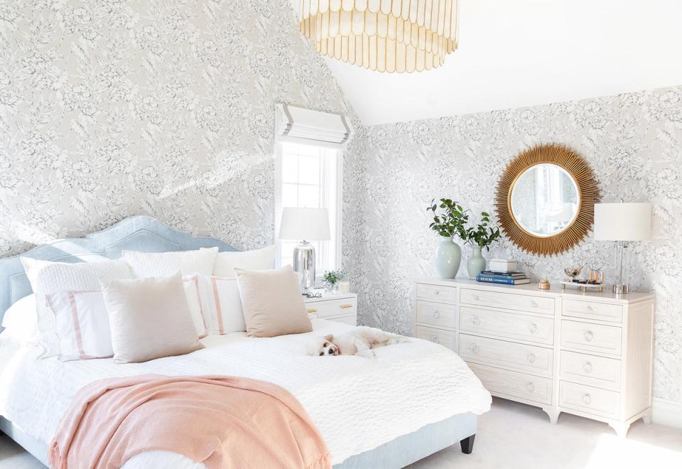 Coastal bedroom with soft pink and blue pillows, light woodwork, and airy aesthetic