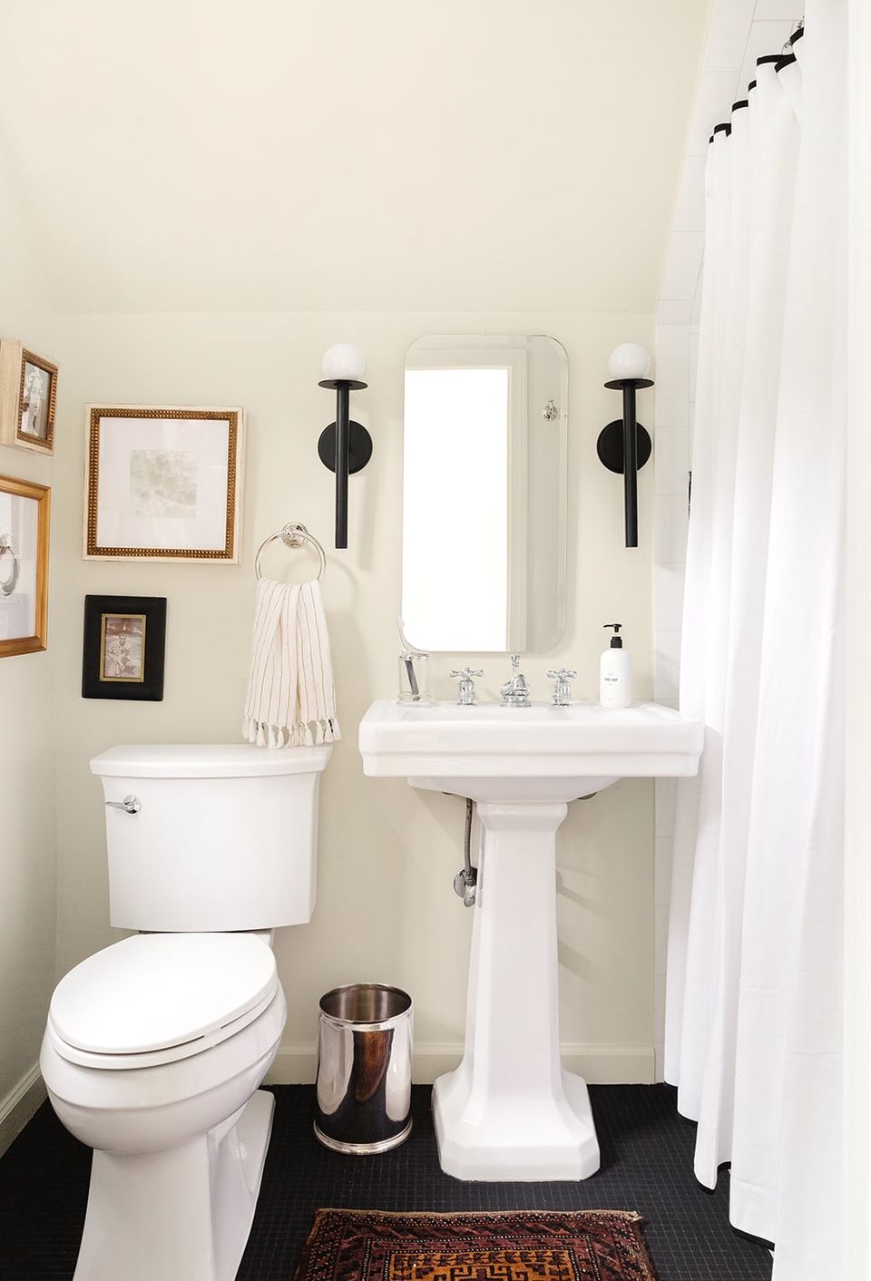 Classic bathroom with warm white walls, pedestal sink, black fixtures, minimalist gallery wall styling