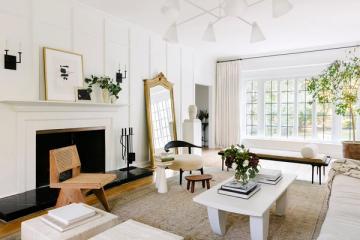 Bright minimalist living room with white walls, matte finish fireplace, natural wood accents, and abundant natural light