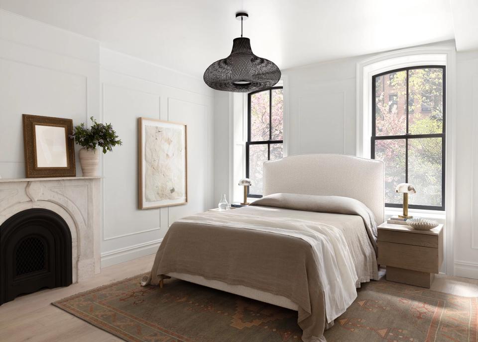Farmhouse bedroom with fireplace, neutral tones, and black metal pendant light.