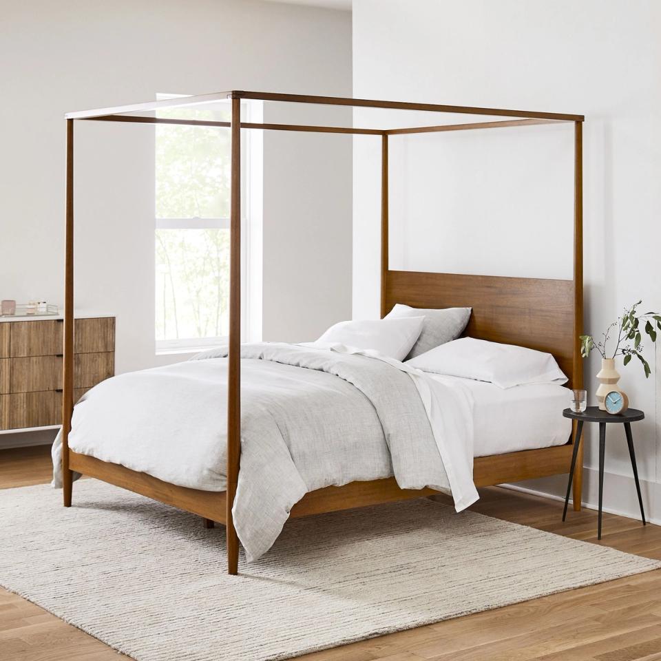 Scandinavian-inspired wooden canopy bed with warm mid-tone finish and minimal styling