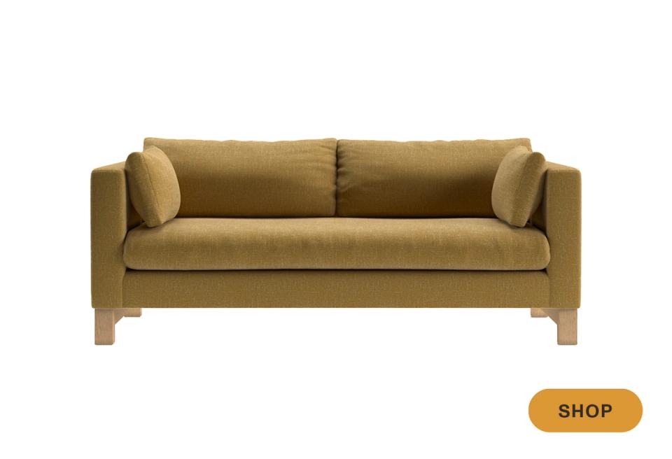 Contemporary sage-green velvet sofa with warm wood base and streamlined design