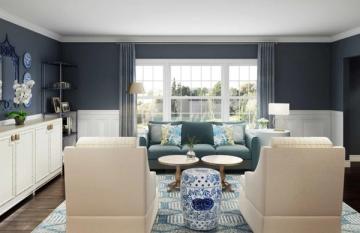 Transitional traditional room with navy upper walls, white paneling, blue sofa, beige chairs, and patterned area rug