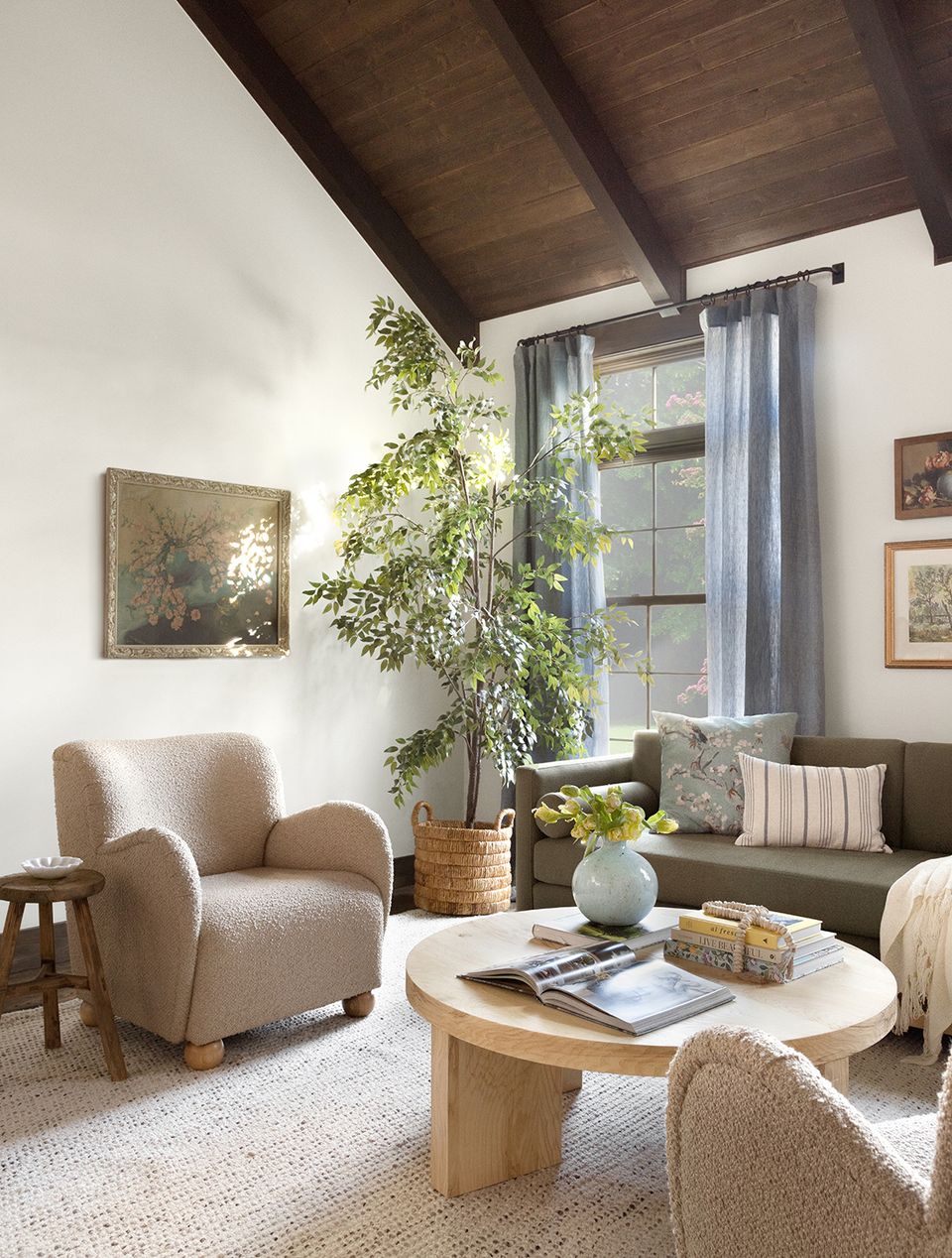 Light-filled modern farmhouse nook with curved beige chair, natural wood coffee table, and abundant greenery.