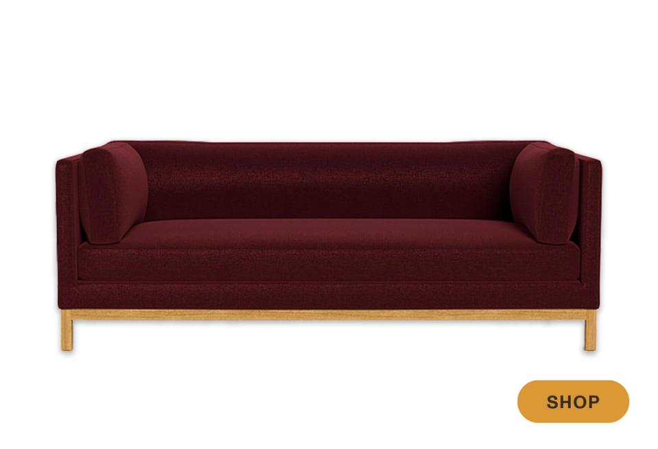 Modern burgundy velvet sofa with minimalist design and natural wood base