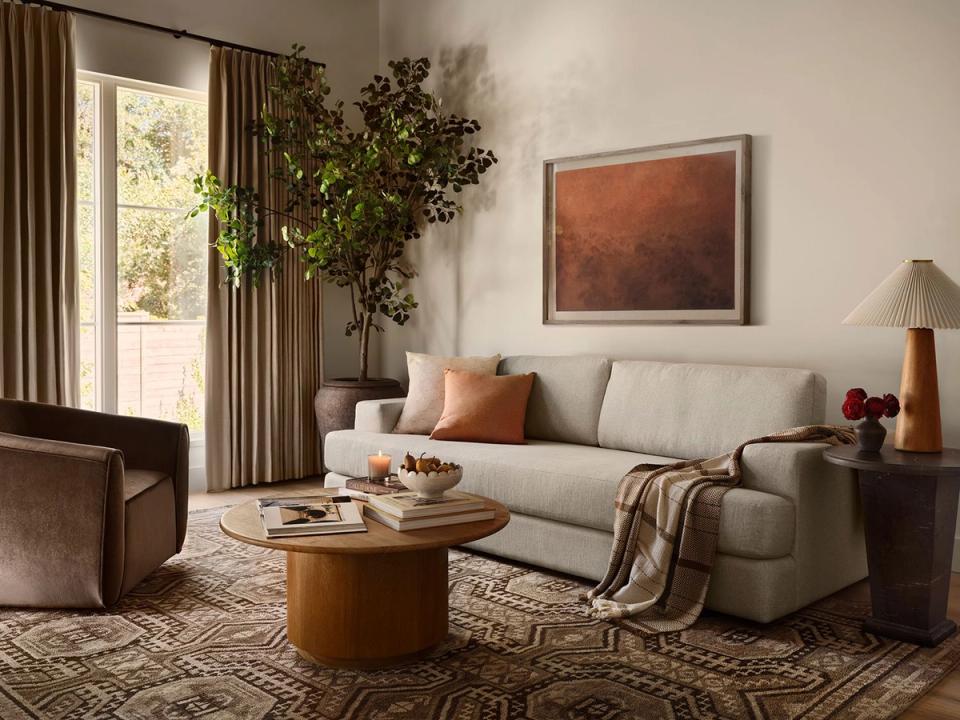 Warm earthy living room with rich brown and terracotta accents, creamy sofa, wood coffee table, and flowing drapery creating a cozy, inviting sanctuary.