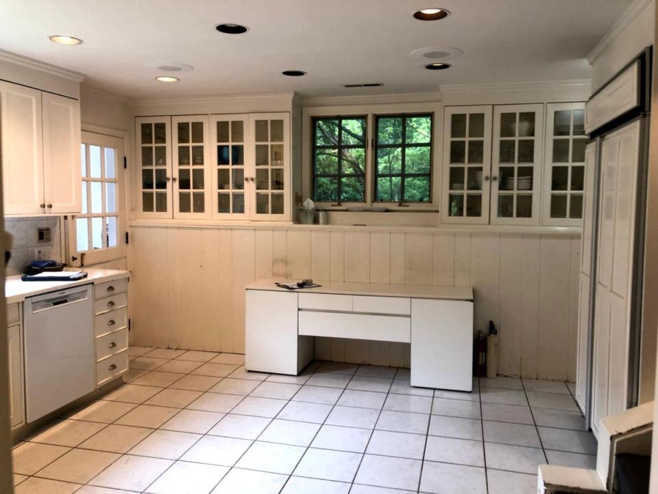 Plain 1990s kitchen with basic white cabinets and dated glass-front upper storage