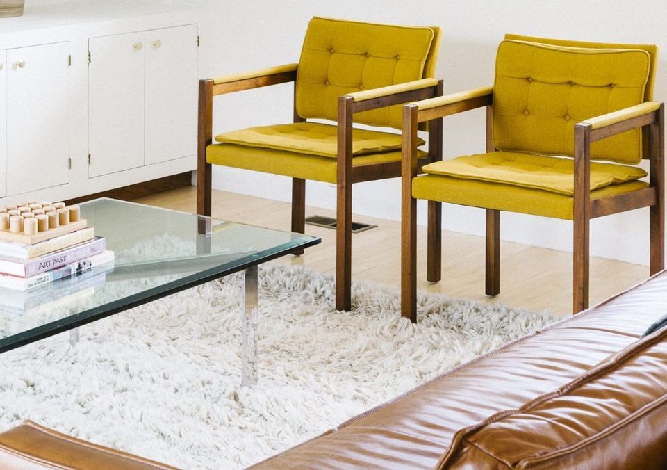 Mid-century modern seating with olive-green chairs, wood frames, and neutral marble coffee table