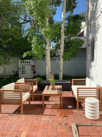 Contemporary mid-century patio with warm wood furnishings, brick flooring, tall trees, and minimalist vibe
