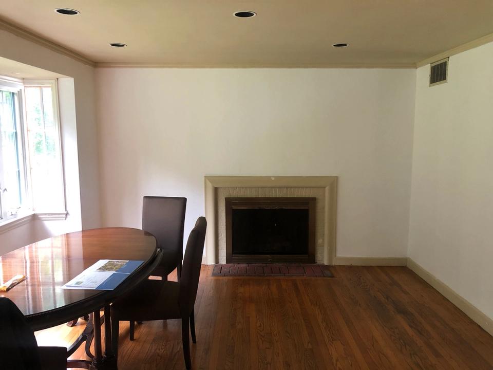 Sparse traditional room with warm wood tones, modest fireplace, and minimal furnishings in neutral palette
