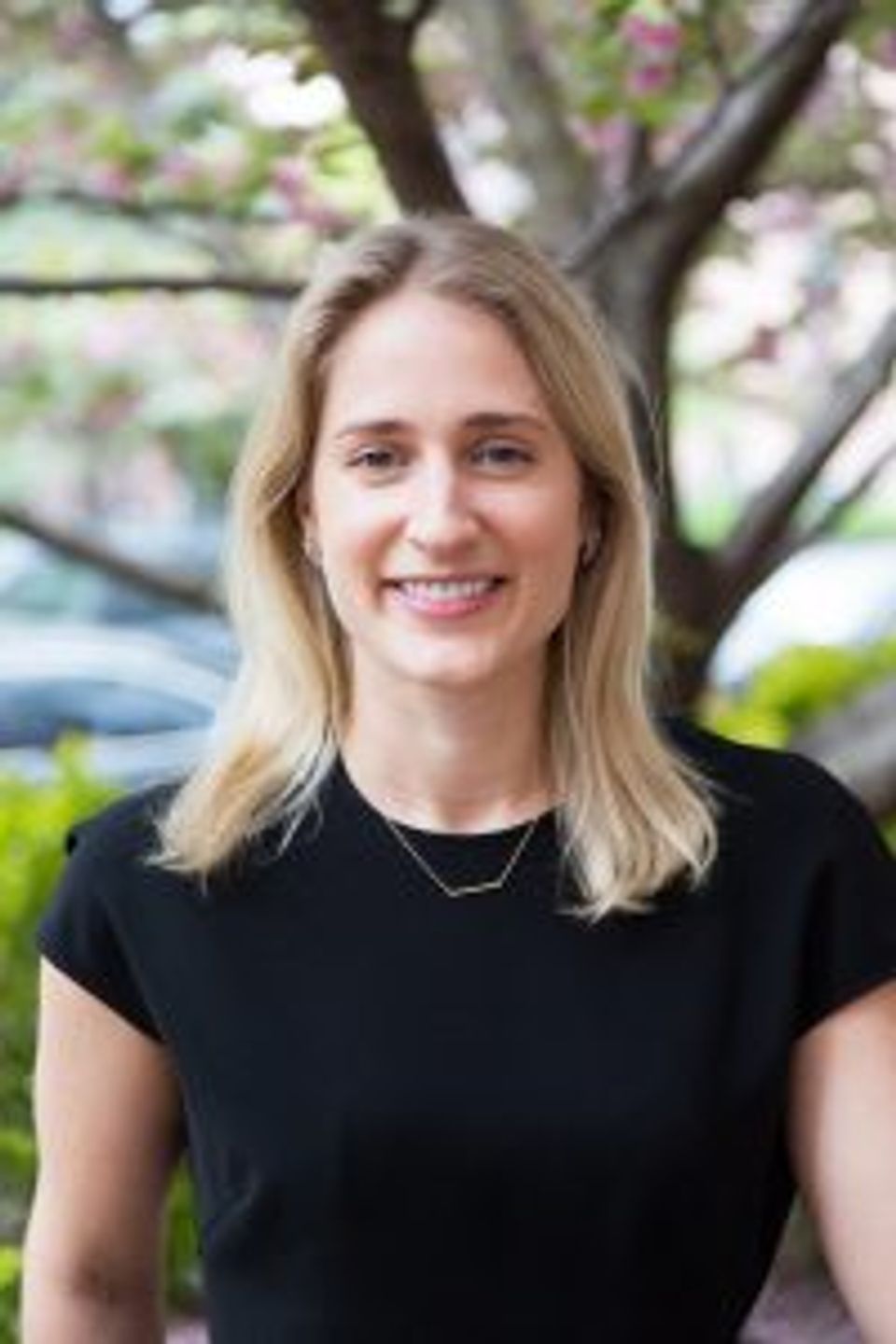 Portrait of smiling woman with blonde hair wearing black shirt outdoors