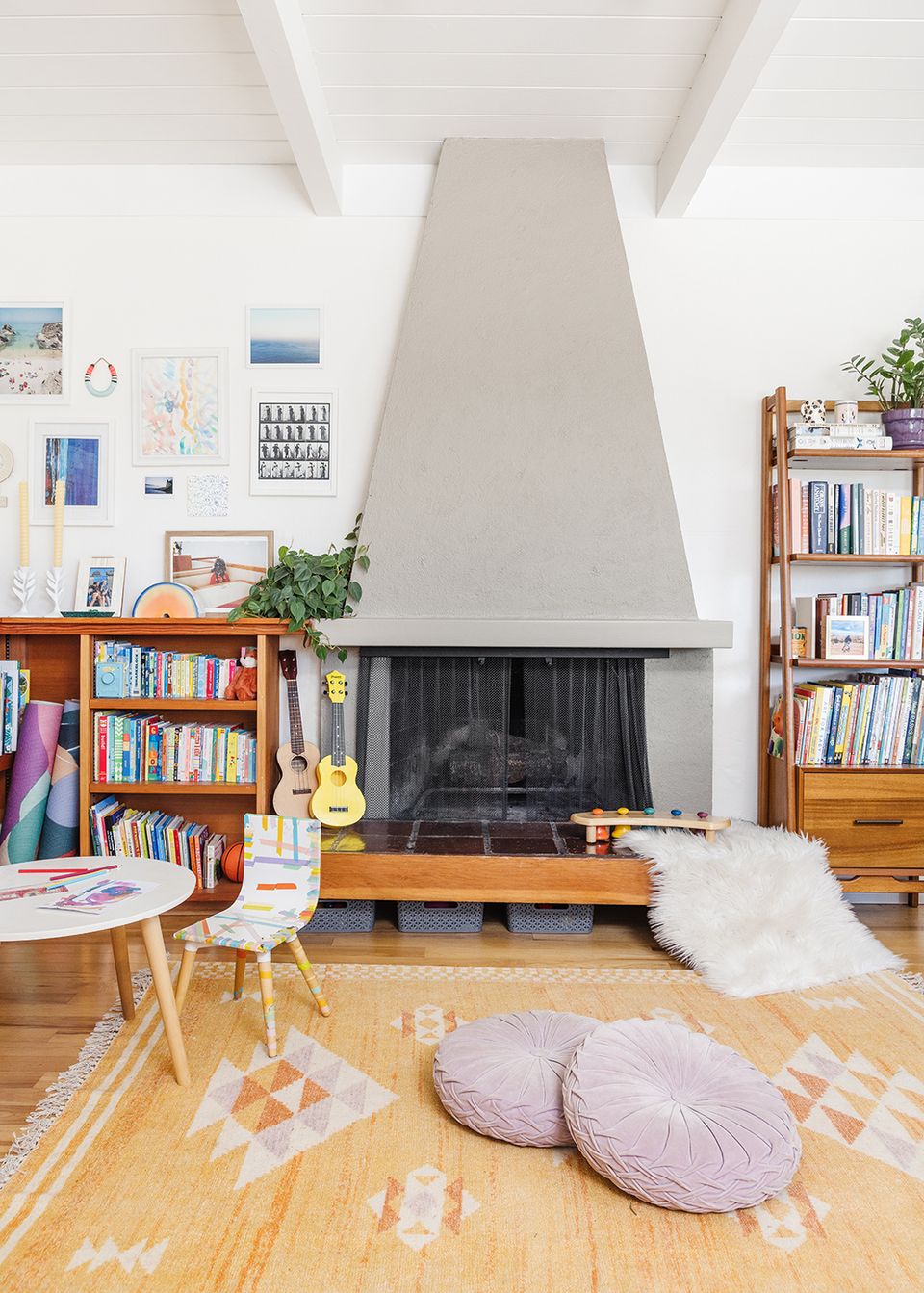Bright, airy mid-century living room with warm wood shelving, geometric patterned rug, and cozy seating around a minimalist fireplace.