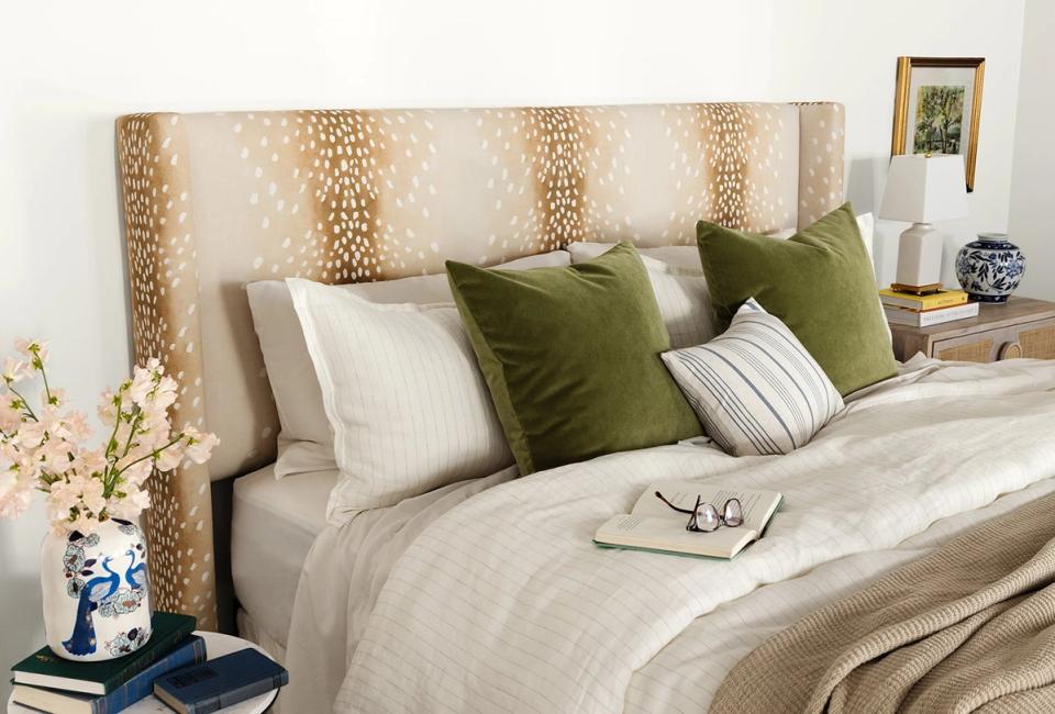 Serene neutral bedroom with patterned headboard, sage green pillows, and layered soft textures in warm minimalist style