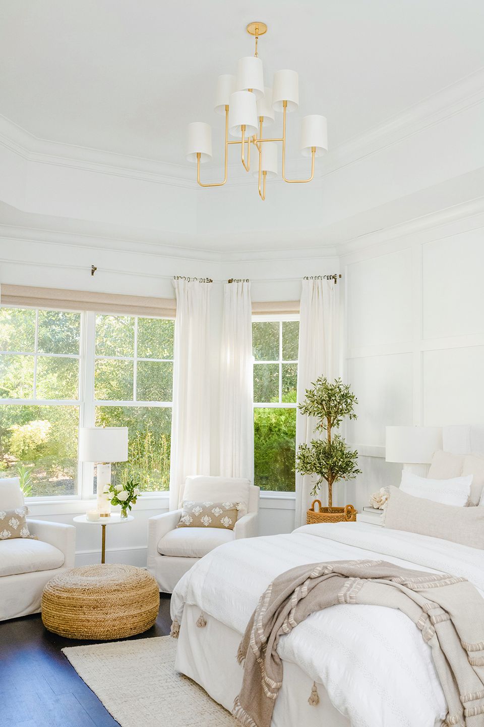 Airy modern bedroom with high ceilings, brass chandelier, white linens, and abundant natural light