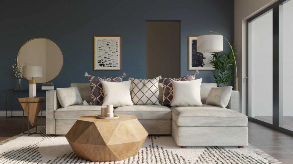 Modern blue living room with cream sectional, geometric wood coffee table, and warm brass accents creating sophisticated, calming atmosphere